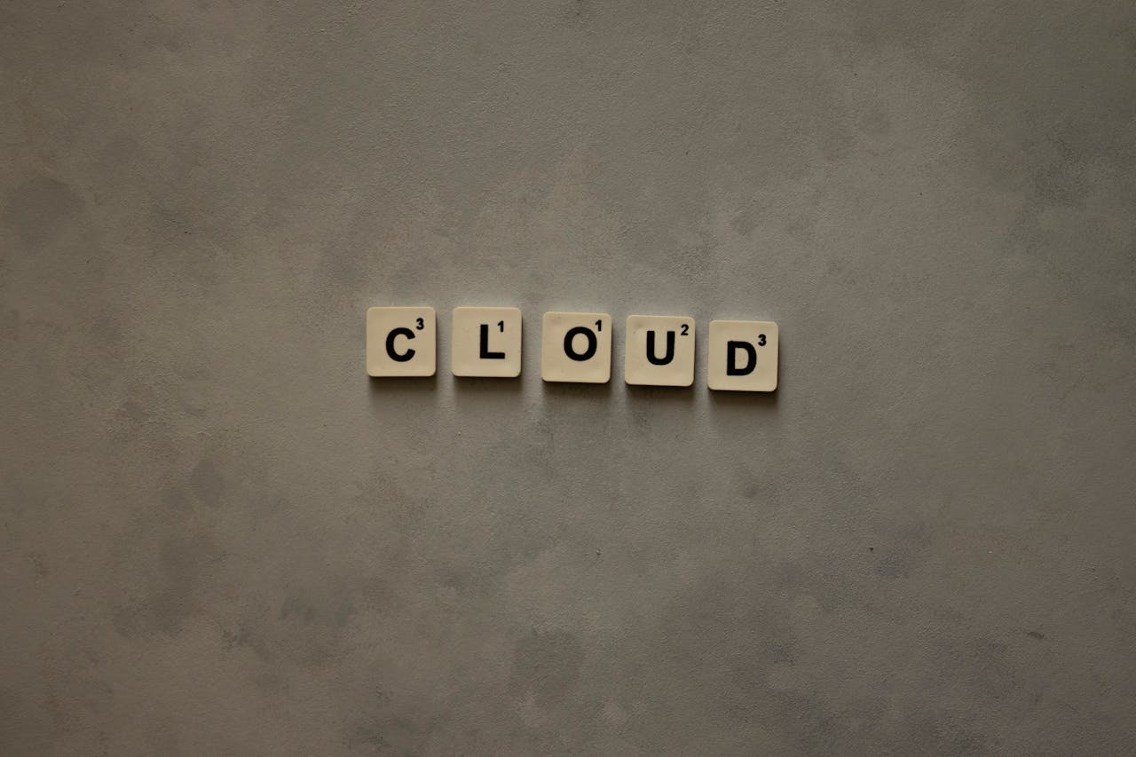 Scrabble tiles arranged to spell 'cloud' on a neutral textured backdrop, creative concept image.